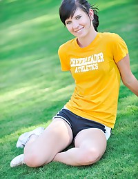 The young babe is in her workout shorts and a t-shirt as she models in the grass.